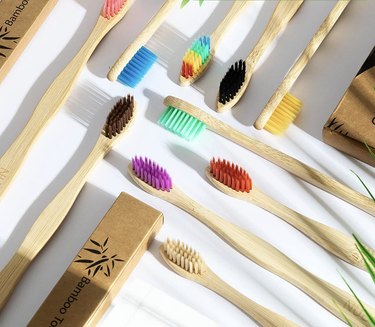 Bamboo toothbrushes with multi-colored bristles like purple, red, brown, yellow, and rainbow.