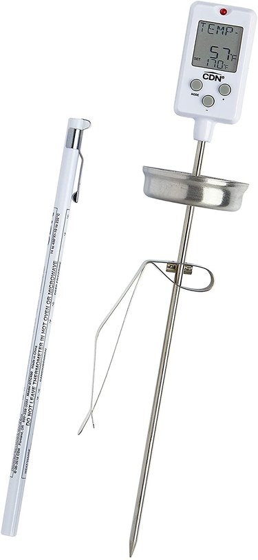 Long CDN candy thermometer pictured with its clip and storage holder, against a white ground