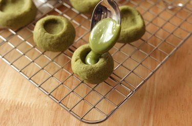 Using a spoon to fill thumbprint cookies with matcha ganache