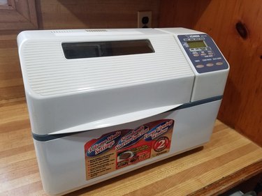 The author's older-model Zojirushi Home Bakery Supreme, shown on a butcher-block countertop with cabinetry visible to the rear.