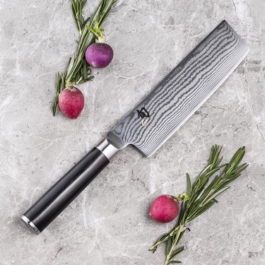 Shun nakiri and fresh vegetables, displayed on a grey marble countertop