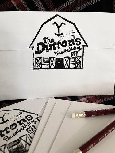 "The Duttons" barn-shaped address stamp on white envelope with two pencils in foreground