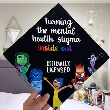 Black graduation cap featuring cartoon characters showing different emotions and the words "turning the mental health stigma inside out OFFICIALLY LICENSED"