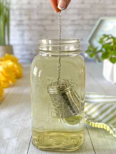 tea ball full of dandelion petals steeping in a jar of water for iced tea