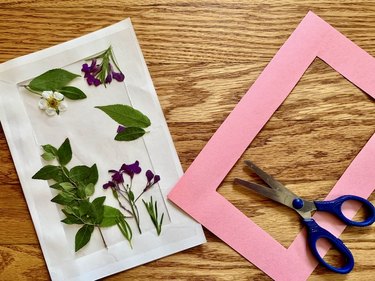 Pressed flower card with a pink frame and pair of scissors next to card