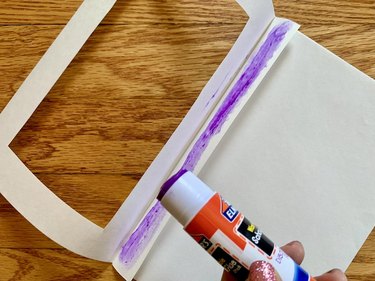 Purple glue stick spread in a straight line on greeting card made of white card stock