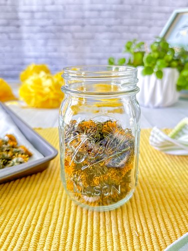 jar filled halfway with dried dandelion flowers