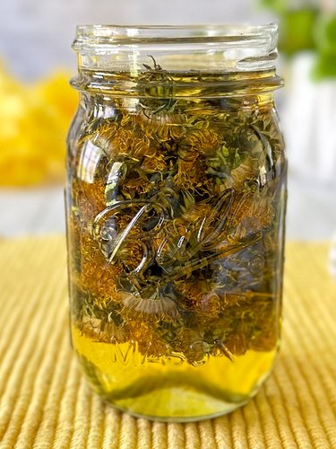 jar filled with dried dandelion flowers and coconut oil