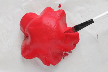 Applying red paint on clay mushroom cap