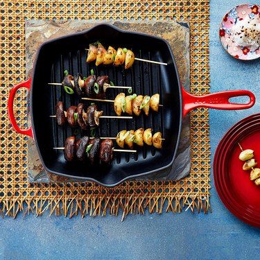 Le Creuset red grill pan on a trivet and cane wicker placemat