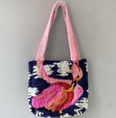 Tufted tote bag featuring a pink flamingo against a dark blue and white background