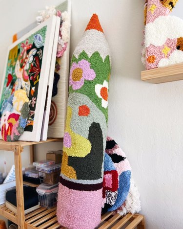 Tufted multicolored pillow shaped like a large pencil