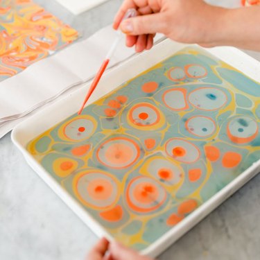 Closeup of paper marbling technique using orange, yellow, and blue colors.