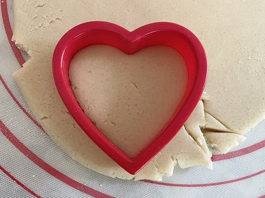 Red heart cookie cutter against sugar cookie dough