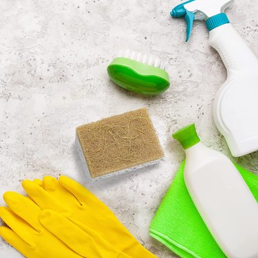 Zen Living eco-friendly sponge on a concrete countertop surrounded by dish gloves and bottles of cleaner.
