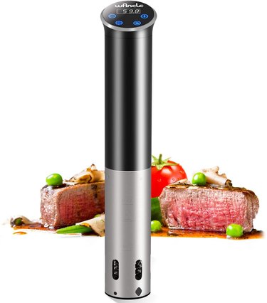 Wancle sous vide circulator on a white ground, with background image of a cooked steak and vegetable garnishes