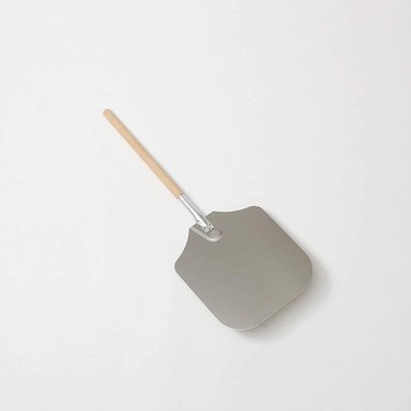American Metaqlcraft pizza peel on an off-white ground