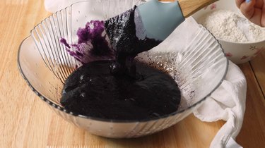 Mixing purple batter in a glass mixing bowl.