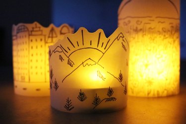 DIY paper lanterns with drawings of mountains, a city skyline and a field of flowers