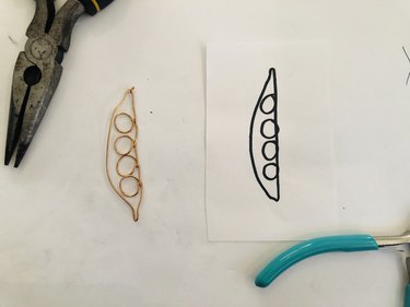 Wire earring shaped like four peas in a pod