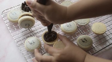 Piping a ring of chocolate ganache on bottom macaron shell