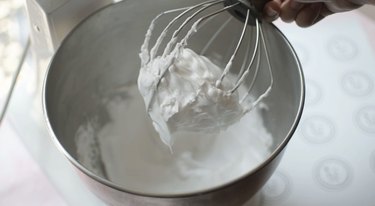 Stiff peak meringue balled up on stand mixer whisk
