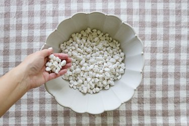 Filling a ceramic planter with small white pebbles