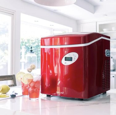 NewAir Portable Ice Maker in red on a countertop next to cold drinks