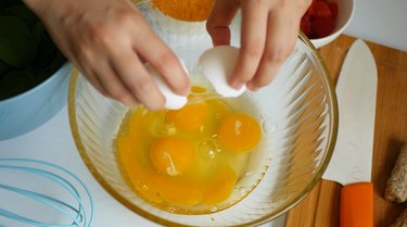 cracking eggs into a clear bowl