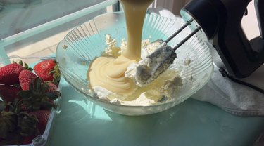 Pouring sweetened condensed milk into glass bowl