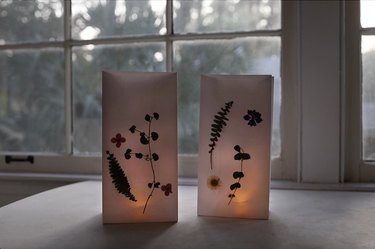 two pressed floral luminaries with lit flameless votives inside