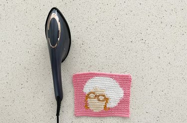 Steam iron next to a crochet panel on a stone tabletop