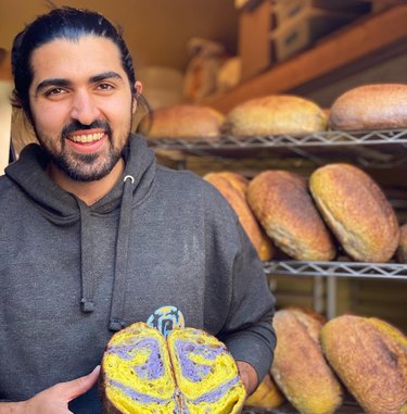 Smiling man holding loaf of purple and yellow bread