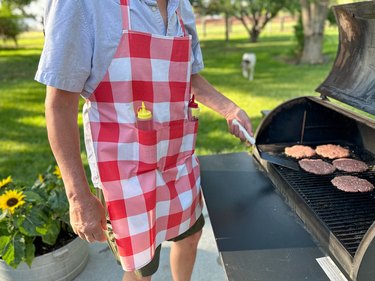 BBQ apron being used while cooking burgers on a grill