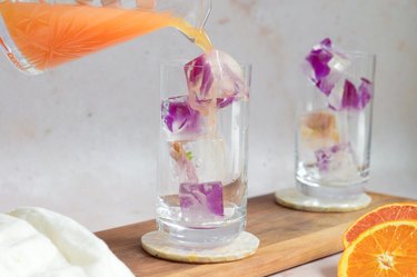 pouring the citrus mixer into glasses with flower ice cubes