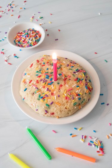 Single-serving birthday cake cookie on plate with candle