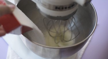 Adding granulated sugar to mixing bowl of egg whites