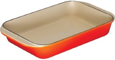 Le Creuset enameled baking dish in a red-orange finish, on a white ground