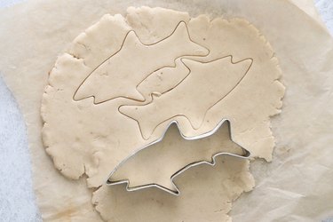 Cutting out sugar cookie dough with shark cookie cutter