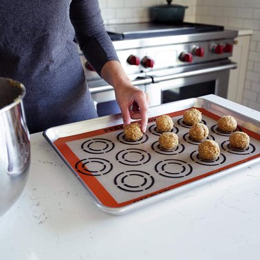 Demarle "Perfect Cookie" baking mat, shown on a counter with a woman placing balls of cookie dough on the mat