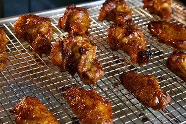 Kitchenatics rack, shown over a sheet pan with roasted chicken wings on it