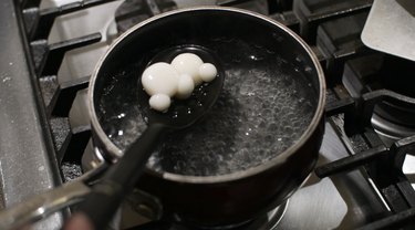 Scooping cooked dango out of simmering water