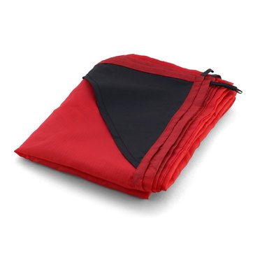 Red picnic blanket folded into a square. The corner pockets and loops are black and help keep the blanket from flying away in windy conditions.