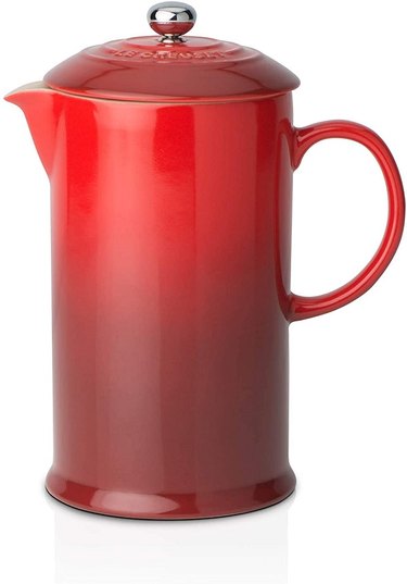 A Le Creuset Stoneware Cafetière in ombre red against a white background.