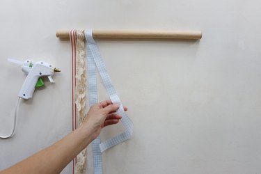 Hot gluing long strips of ribbon onto wood dowel