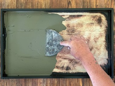 Hand using metal tool to spread green mortar