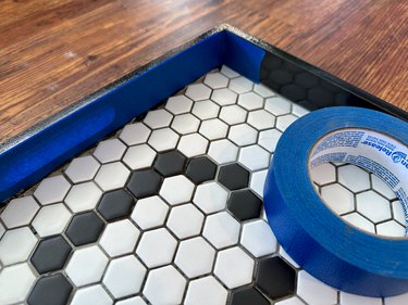 Blue painter's tape attached to side of black and white tile tray