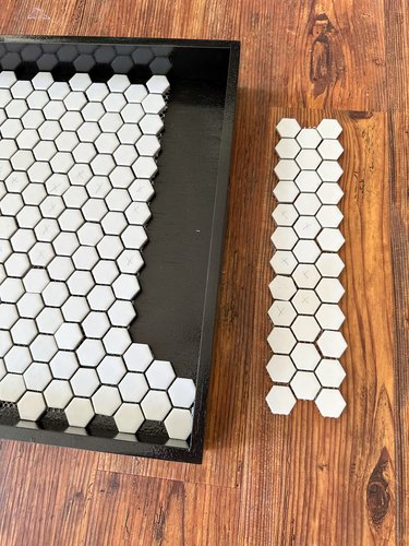 White tiles arranged in a strip next to black tray and more tiles