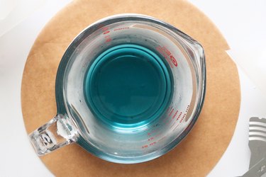 Turquoise candle wax in a glass measuring cup