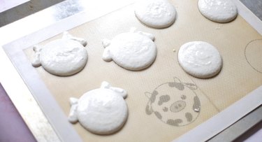 Piped cow macarons on silicone mat